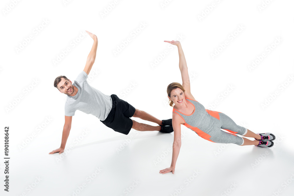 smiling sportive couple exercising together isolated on white