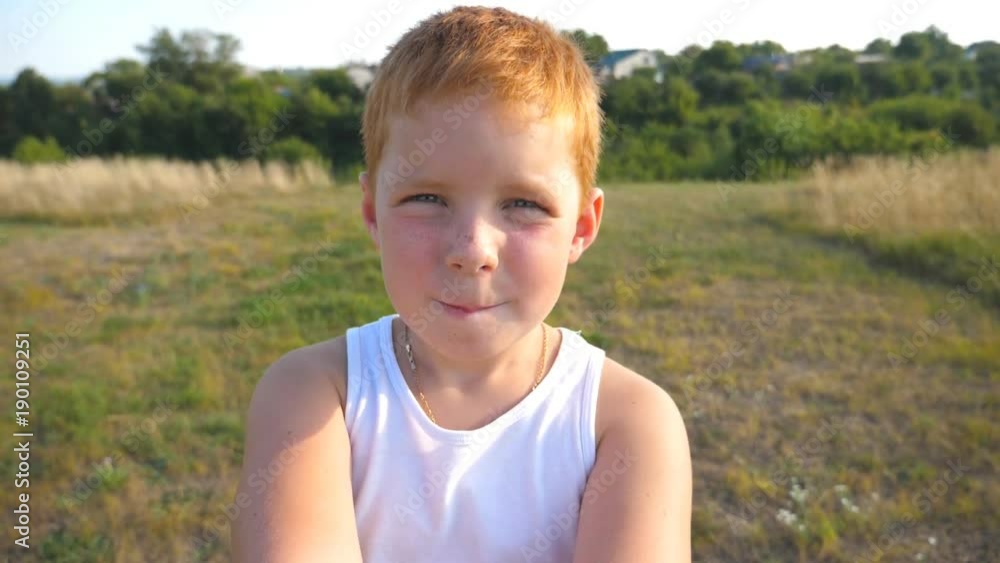 Handsome baby looking with interest to the camera that he holds in his hands. Close up emotions of male child with serious expression on face. Portrait of red hair boy with freckles. Slow motion Handsome baby looking with interest to the camera that he holds in his hands. Close up emotions of male child with serious expression on face. Portrait of red hair boy with freckles. Slow motion