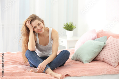 Portrait of beautiful smiling woman on bed at home