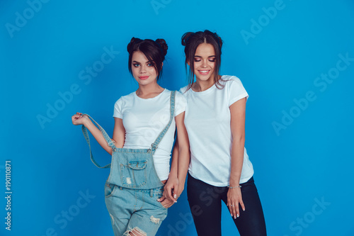 Attractive women in a white t-shirts stands on a blue background. Mock-up.