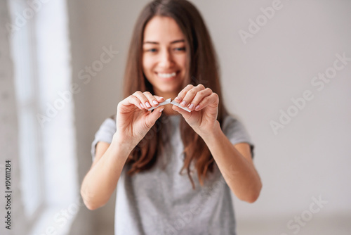 Stop smoking cigarettes concept. Portrait of beautiful smiling girl holding broken cigarette in hands. Happy female quitting smoking cigarettes. Quit bad habit, health care concept. No smoking.