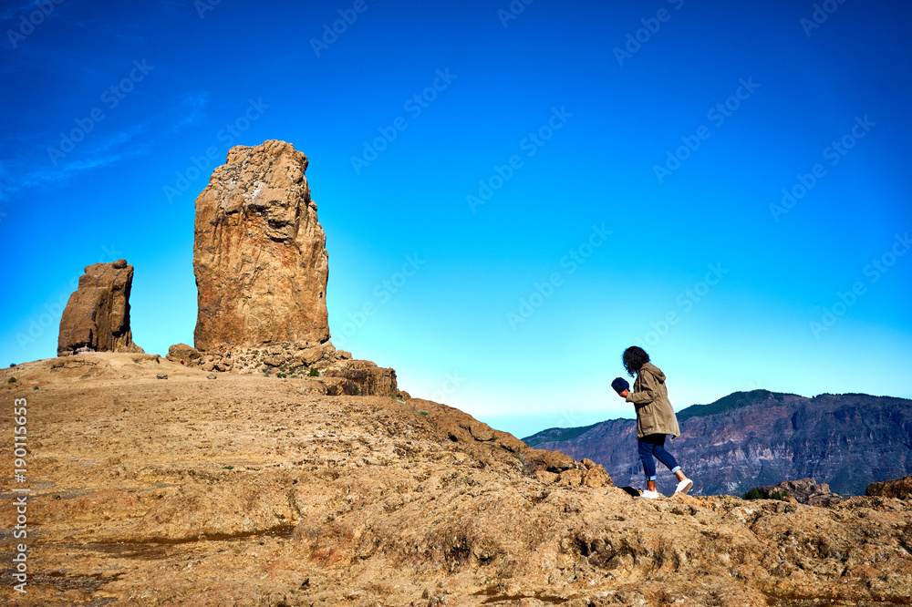 Woman hiking on trail to Roque Nublo - Gran Canaria - Tejeda - Blue sky over Canary Islands