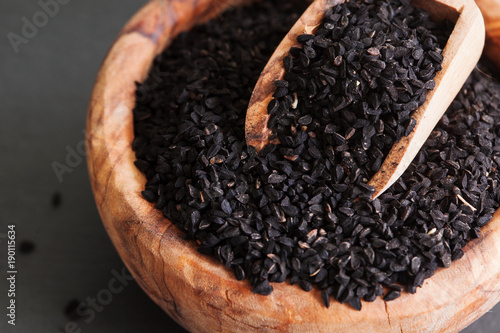 Black cumin or nigella sativa or kalonji seeds in bowl with spoon on black slate background, selective focus