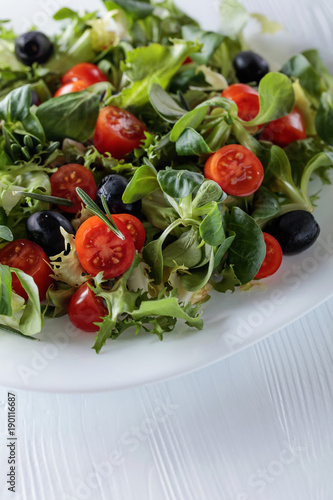 Green salad with tomatoes and black olives.