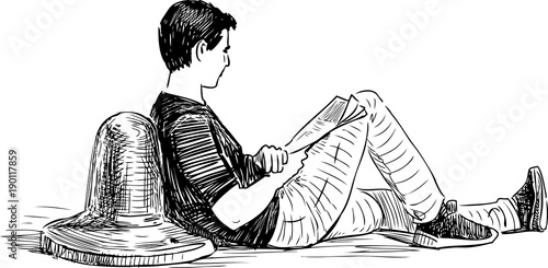 A young man reads a newspaper on an embankment