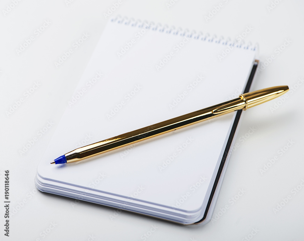 Notepad with blank paper next to golden ball pen on white background. Isolated. Mockup. Notepad with blank paper next to golden ball pen on white background. Isolated. Mockup.