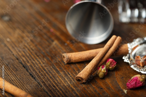 cinnamon on the bar counter, on a wooden background. next to it are dried rosebuds..