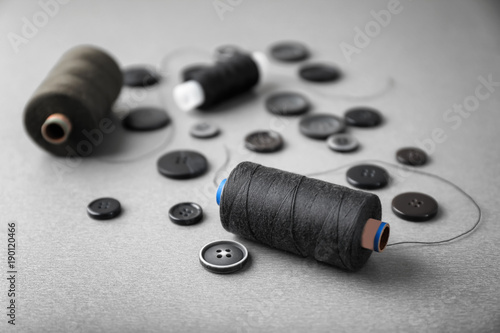 Dark sewing threads with buttons on grey background