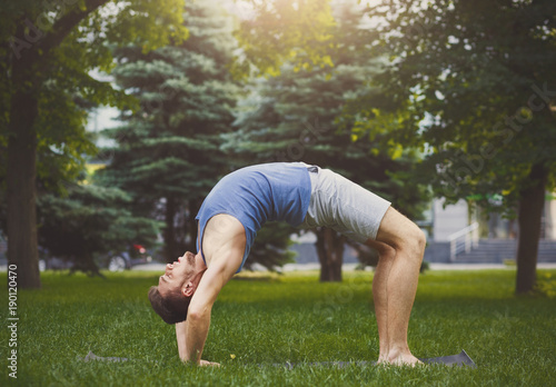 Man training yoga in table top pose outdoors