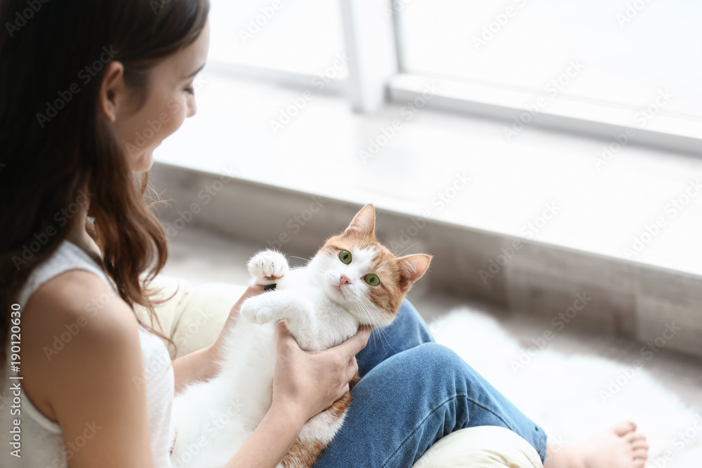 Beautiful young woman with cute cat near window at home Beautiful young woman with cute cat near window at home