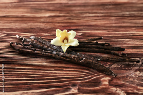 Vanilla sticks and flower on wooden background
