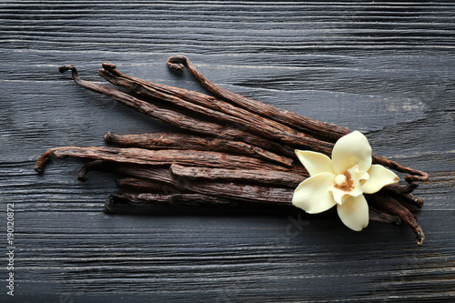 Vanilla sticks and flower on wooden background