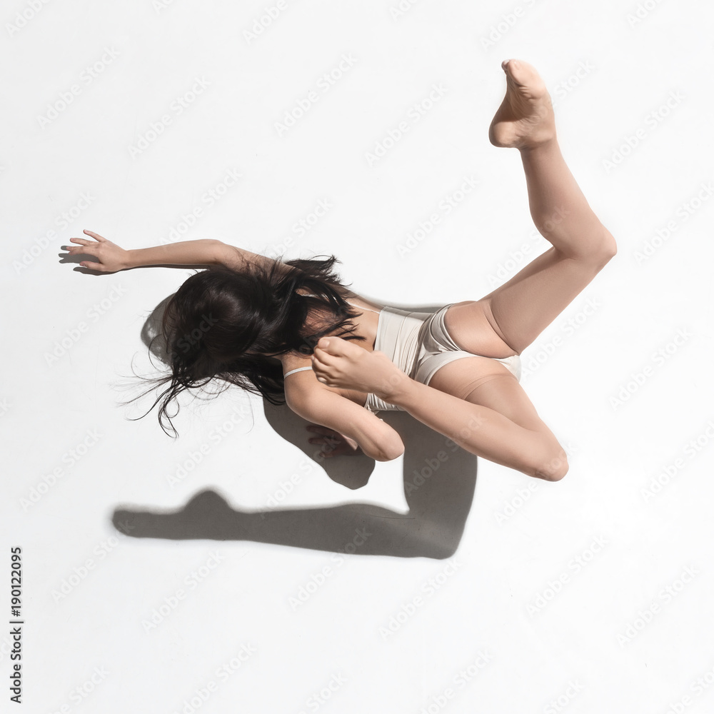 Young beautiful dancer in beige dress dancing on gray background Young beautiful dancer in beige dress dancing on gray background
