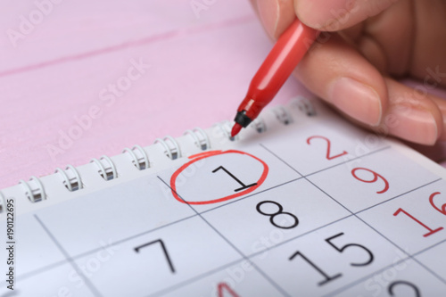 Woman circling date on calendar, closeup. April fool's day celebration
