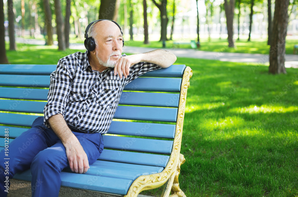 Fototapeta premium Pensive senior man in earphones outdoors