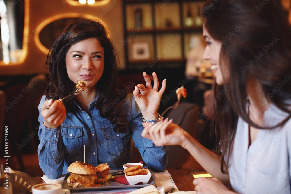 Two young women at lunch in a restaurant - obrazy, fototapety, plakaty 