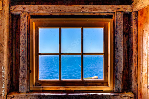 Looking through old rustic window of house with ocean view in Bonaventure Island  Quebec  Canada