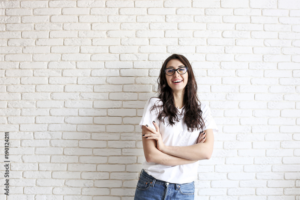 Happy millennial girl having fun indoors. Portrait of young woman with diastema gap between teeth. Beautiful smile. Minimalistic interior, white brick textured wall background, loft style. Copy space. Happy millennial girl having fun indoors. Portrait of young woman with diastema gap between teeth. Beautiful smile. Minimalistic interior, white brick textured wall background, loft style. Copy space.