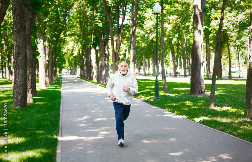 Elderly man running in green park, copy space Elderly man running in green park, copy space