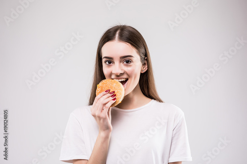 Woman biting burger isolated portrait on gray background. health concept.