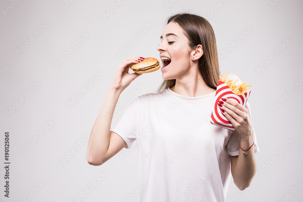 woman biting hamburger on gray background woman biting hamburger on gray background
