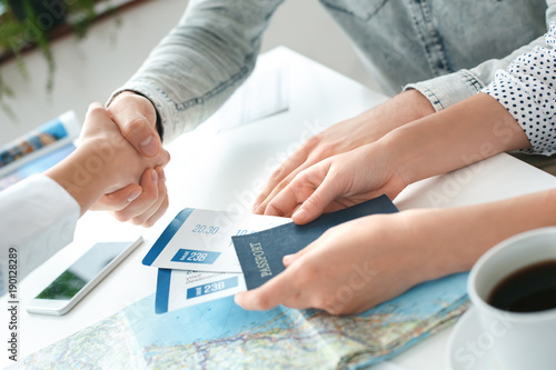 Young couple in a tour agency communication with a travel agent travelling concept shaking hands