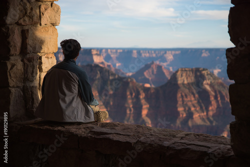 A man sitting and looking out towards the Grand Canyon in Arizona. 