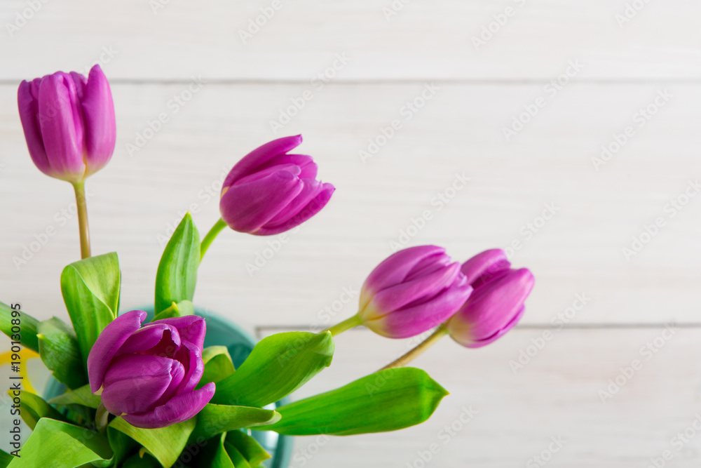 Violet tulips bouquet on white wood background, top view
