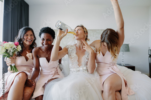 Bride and bridesmaids enjoying before wedding in hotel room