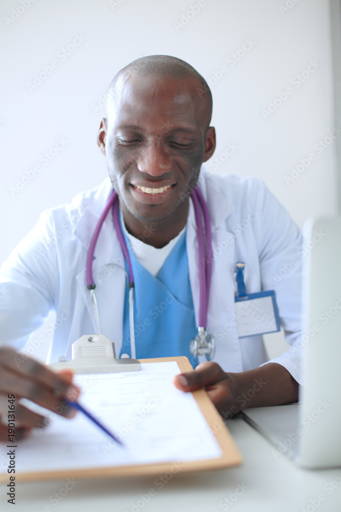 Portrait of young male doctor wearing headset while using computer at desk in clinic. Doctor. Portrait of young male doctor wearing headset while using computer at desk in clinic. Doctor.