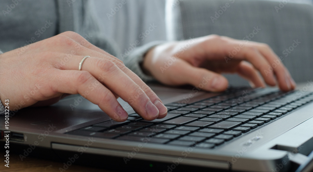 Closeup of young man hands with marriage ring typing on keyboard Closeup of young man hands with marriage ring typing on keyboard
