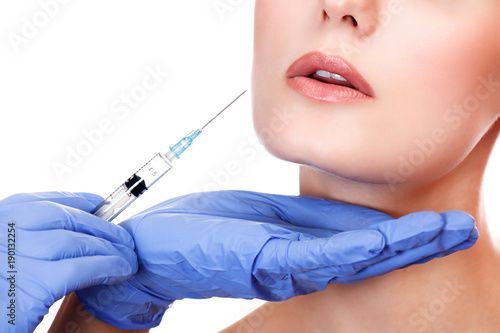 Closeup shot of a doctor s hands who make a beauty injection into the lips of a patient.