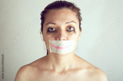 Unhappy woman with wrapping her mouth by adhesive tape painted smile photo