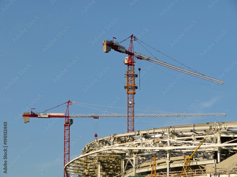Construction site. Construction cranes and building on the background of blue sky Construction site. Construction cranes and building on the background of blue sky