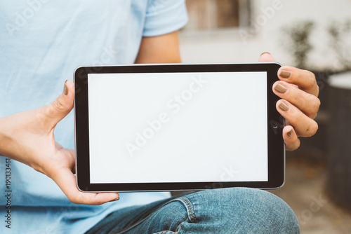 Hand holding black mobile tablet with blank white screen at outdoor to checking e-mail or social network. technology and lifestyle concept.