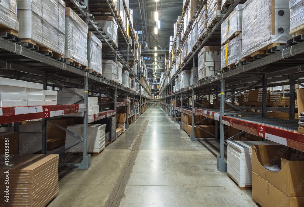Large warehouse logistic or distribution center. Interior of warehouse with rows of shelves with big boxes
