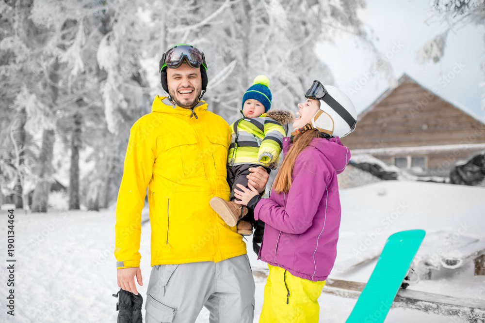 Portrait of a happy family with baby boy standing in winter spots clothes outdoors during the winter vacations