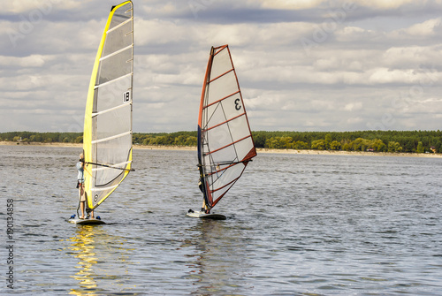 A pair of windsurfing plays in the waves, in the vastness of the reservoir