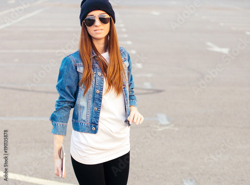 Female teen sits iasphalt road in urban wear and hat photo