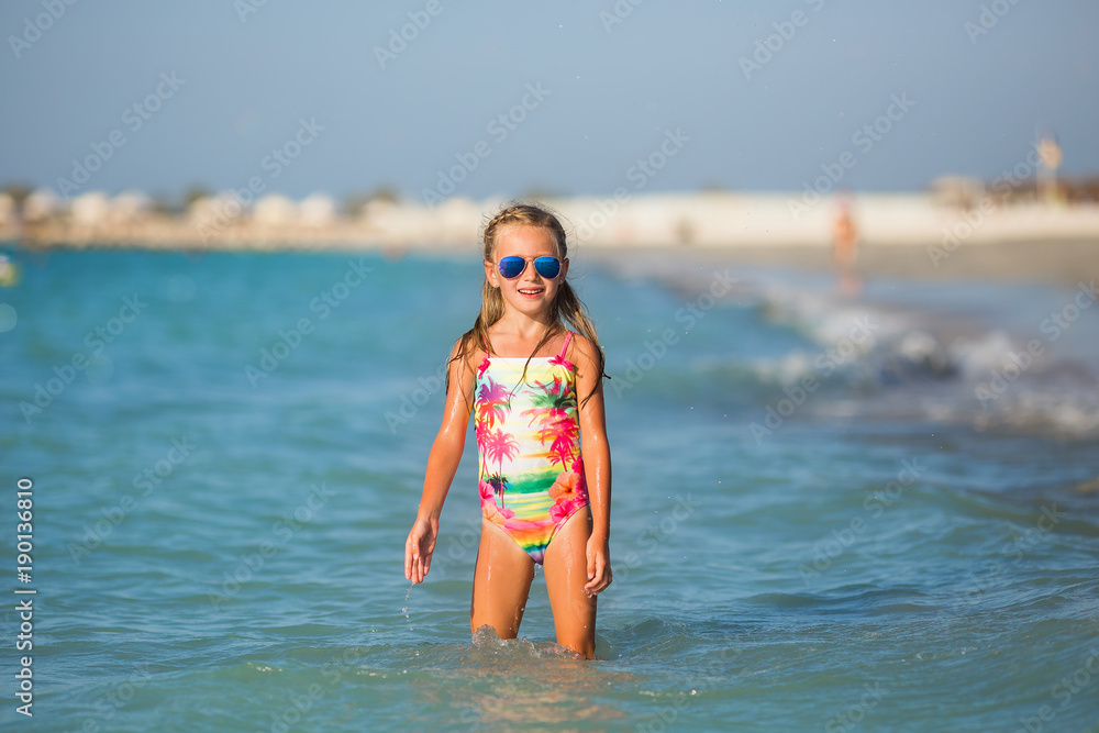 Little girl laughing in the spray of waves at sea on a sunny day
