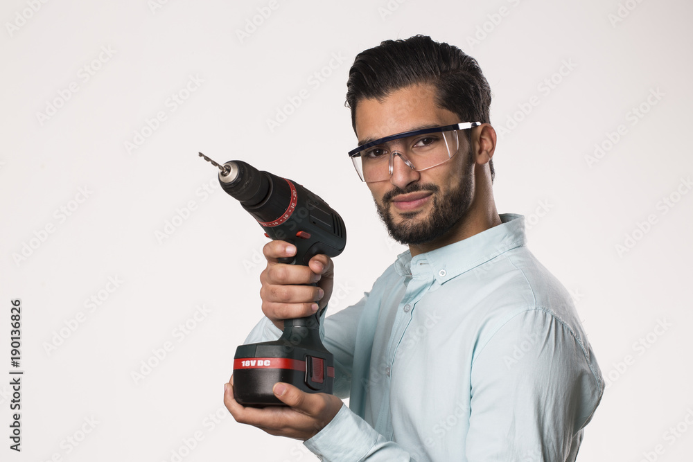young man with a drill wearing protection glasses young man with a drill wearing protection glasses