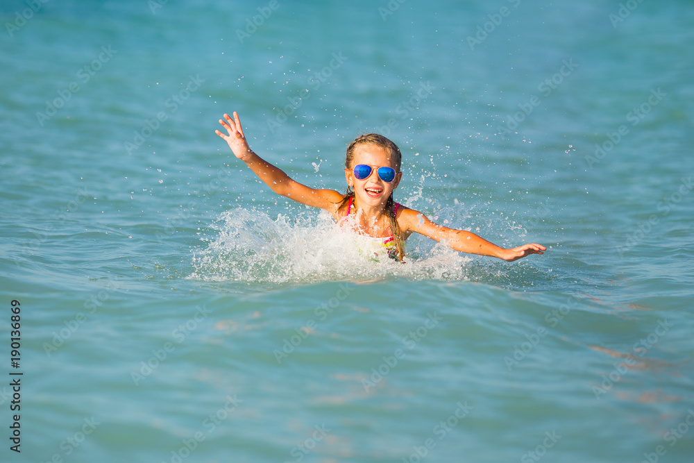 Cute young girl playing in the sea.  Happy pre-teen girl enjoys summer water and holidays in holiday destinations.