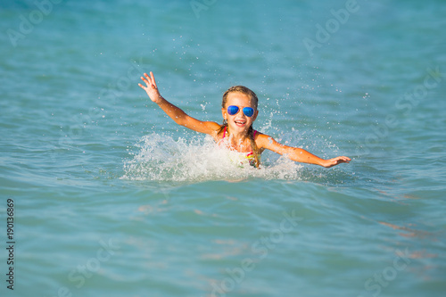 Cute young girl playing in the sea. Happy pre-teen girl enjoys summer water and holidays in holiday destinations.