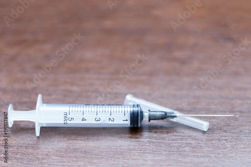 The syringe with the open needle on the table
