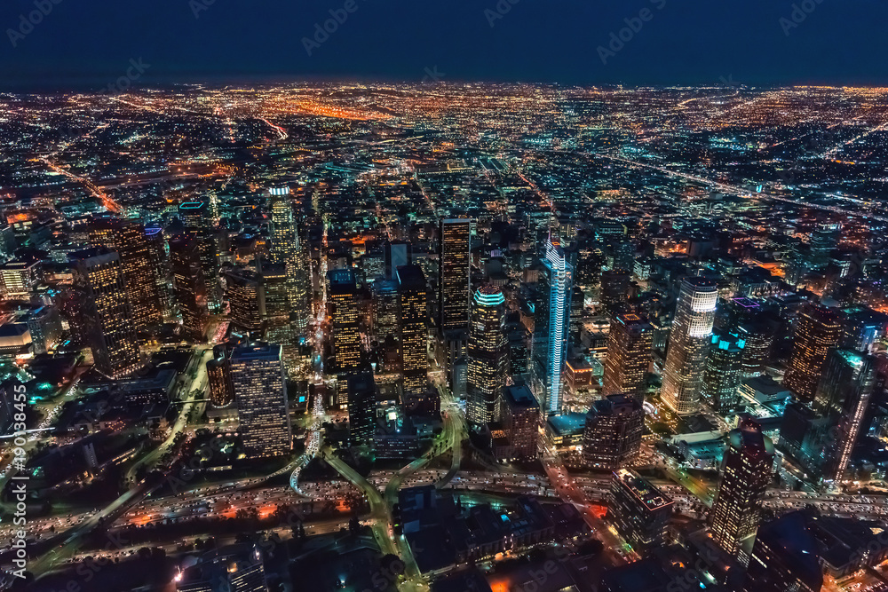 Fototapeta premium Aerial view of Downtown Los Angeles at twilight with young woman holding out a smartphone in her hand