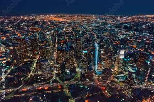 Aerial view of Downtown Los Angeles at twilight with young woman holding out a smartphone in her hand