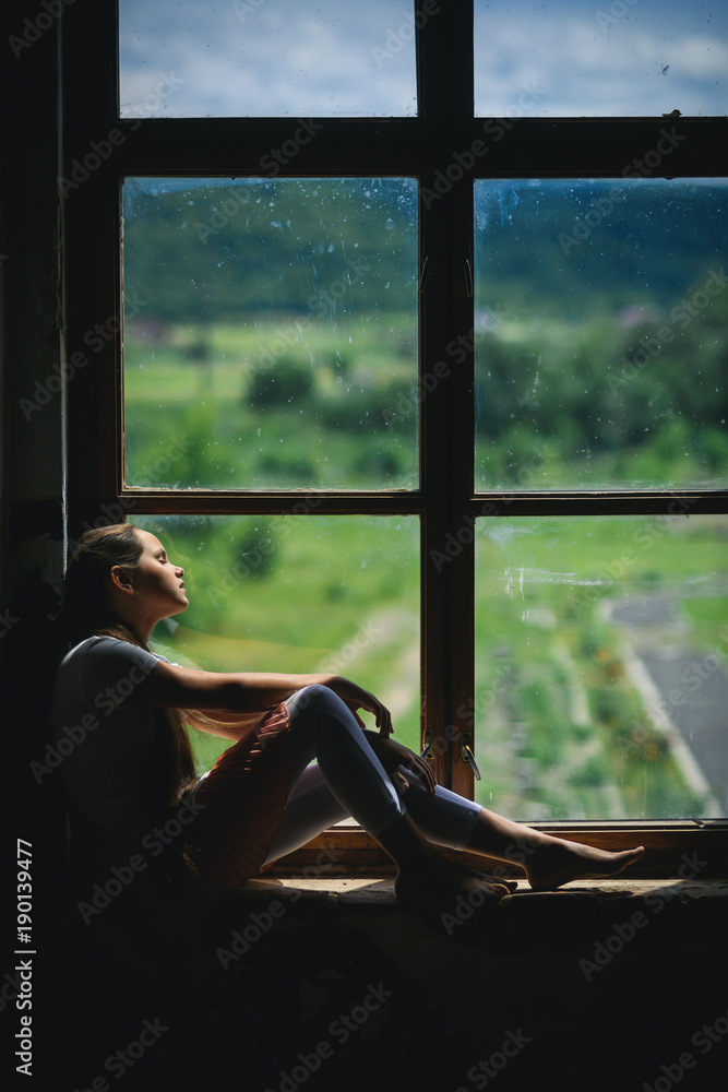 Young girl sleep on window sill with summer landscape view