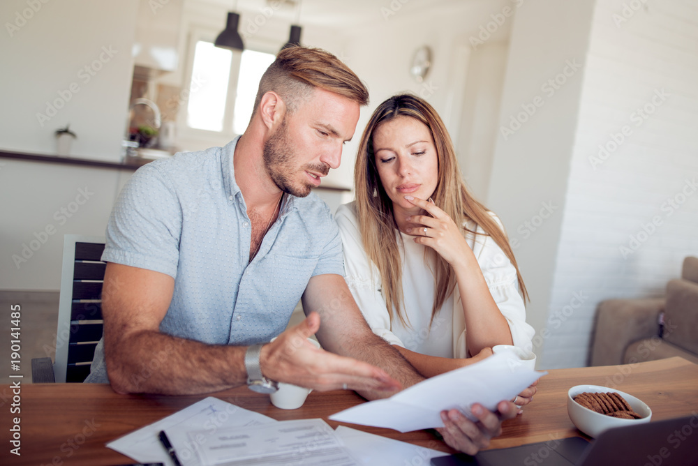 Couple doing their accounting with a laptop in their living room. Couple doing their accounting with a laptop in their living room.