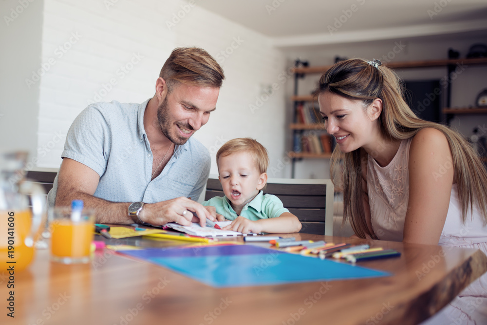 Smiling family drawing together in kitchen at home Smiling family drawing together in kitchen at home