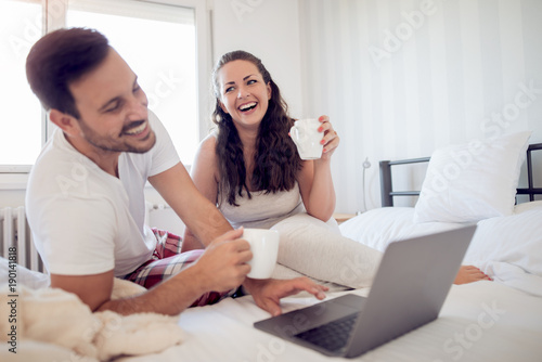 Young couple with laptop in the bed.
